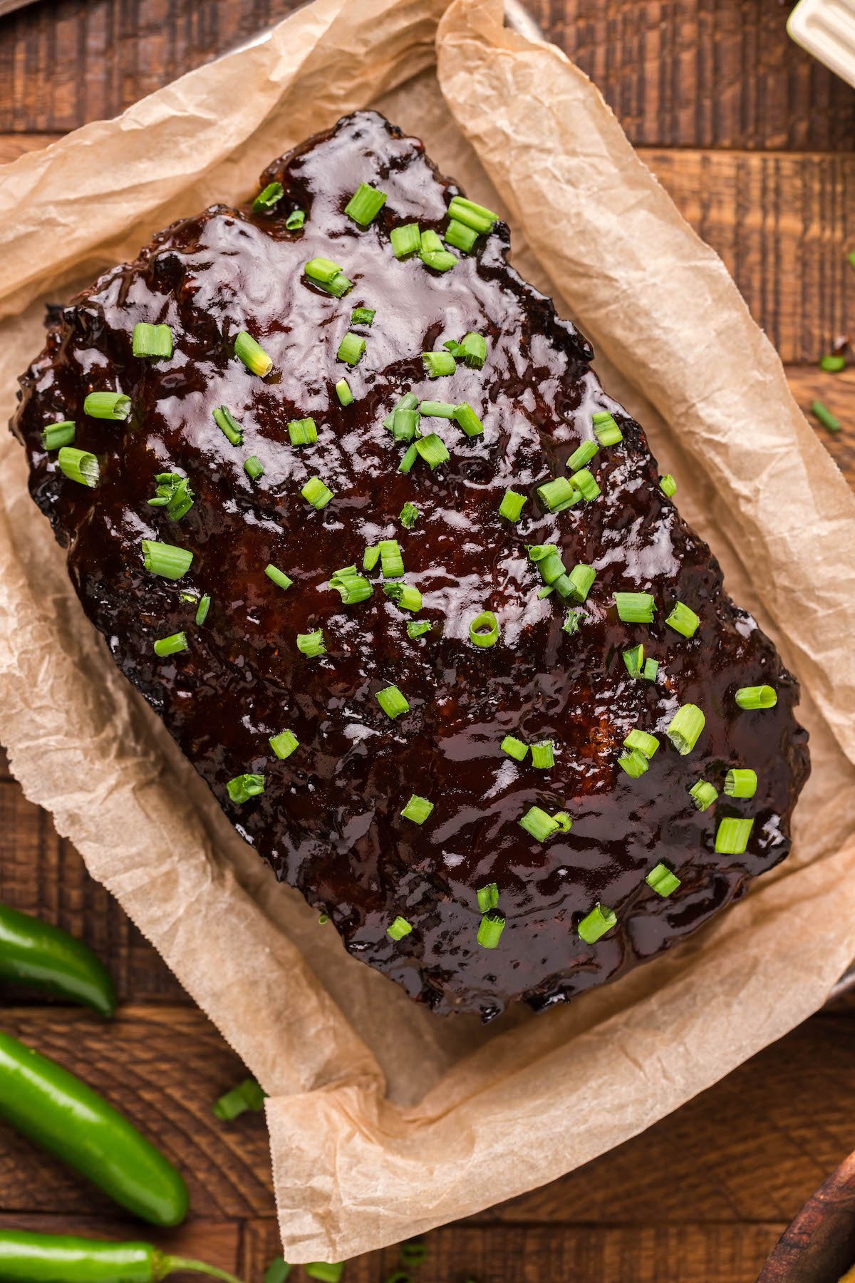 Overhead view of meatloaf covered in bbq sauce and garnished with green onion slices.