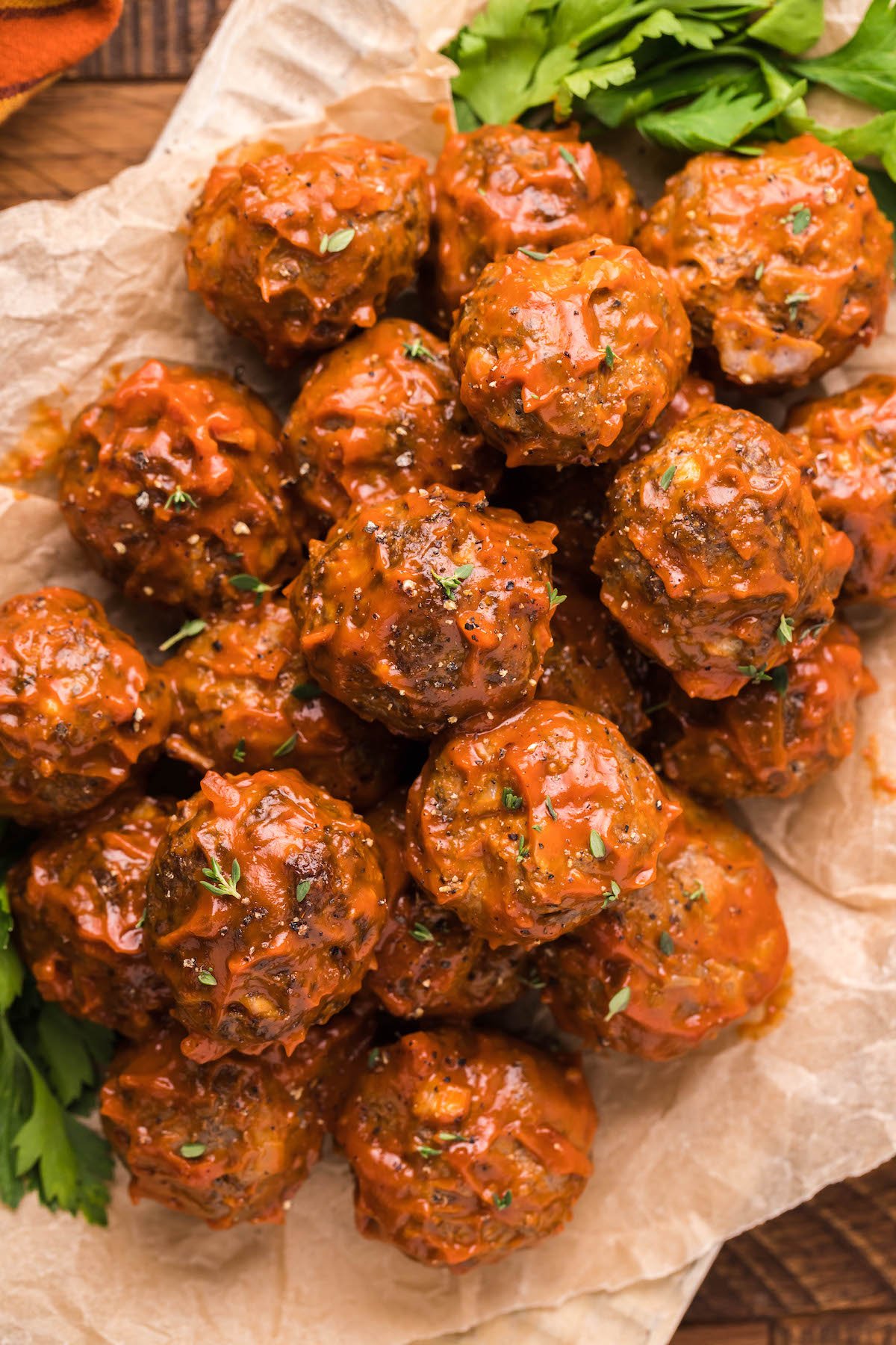 A few dozen bison meatballs covered in BBQ sauce on brown paper. 