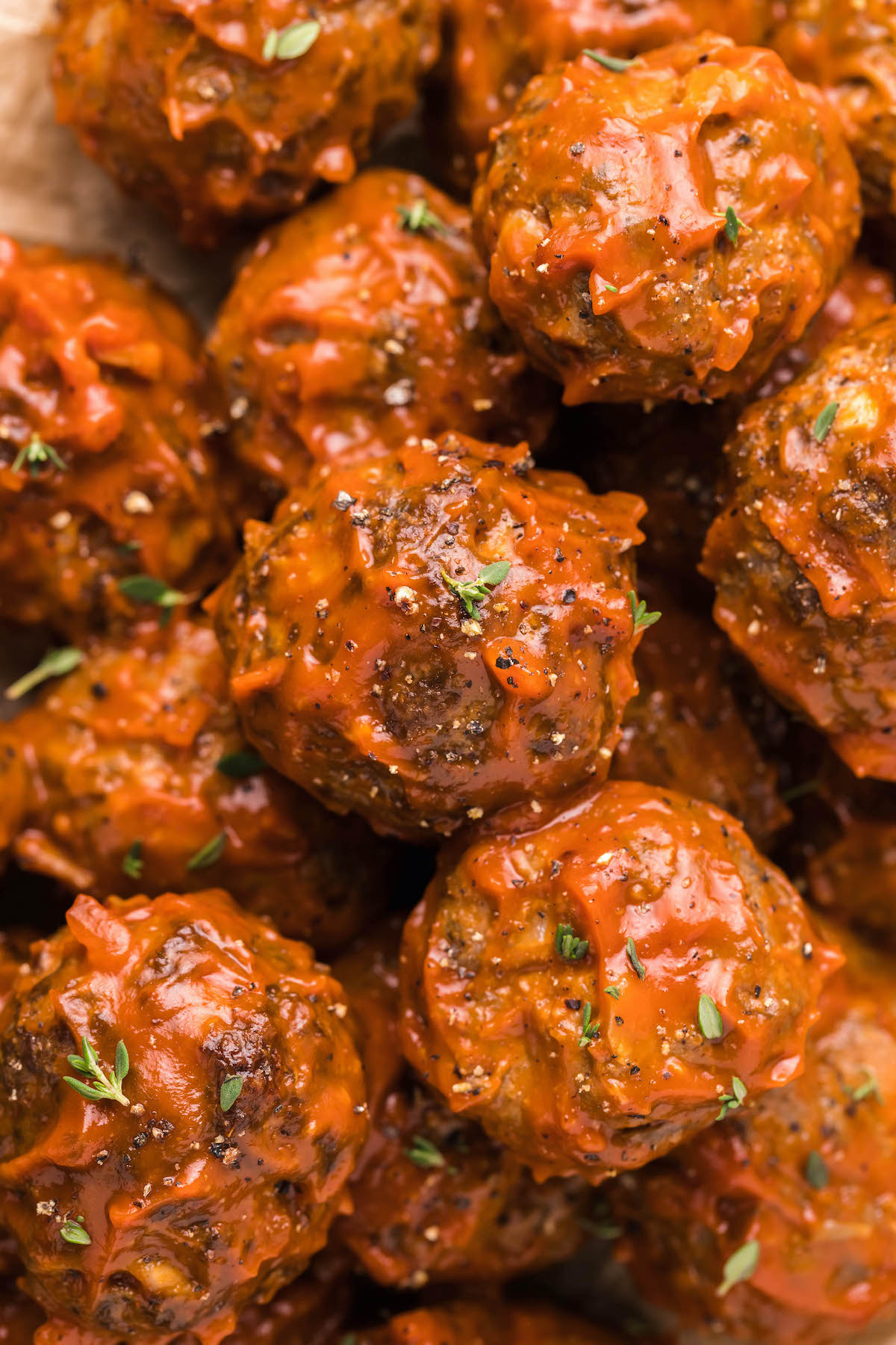 Close up of several Bison Meatballs lightly covered in BBQ sauce.