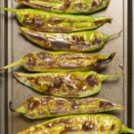 Overhead view of a baking sheet filled with green roasted Hatch Chiles.