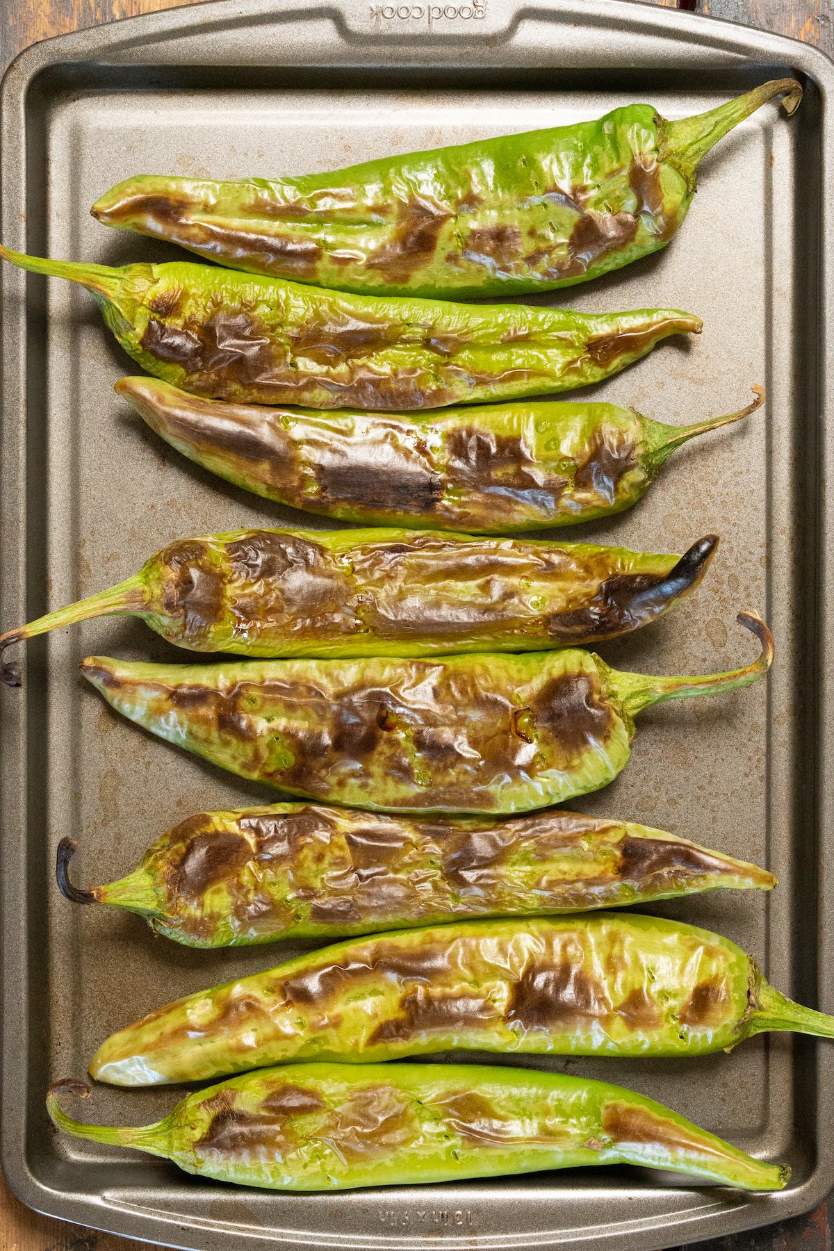 Overhead view of a baking sheet filled with green roasted Hatch Chiles.