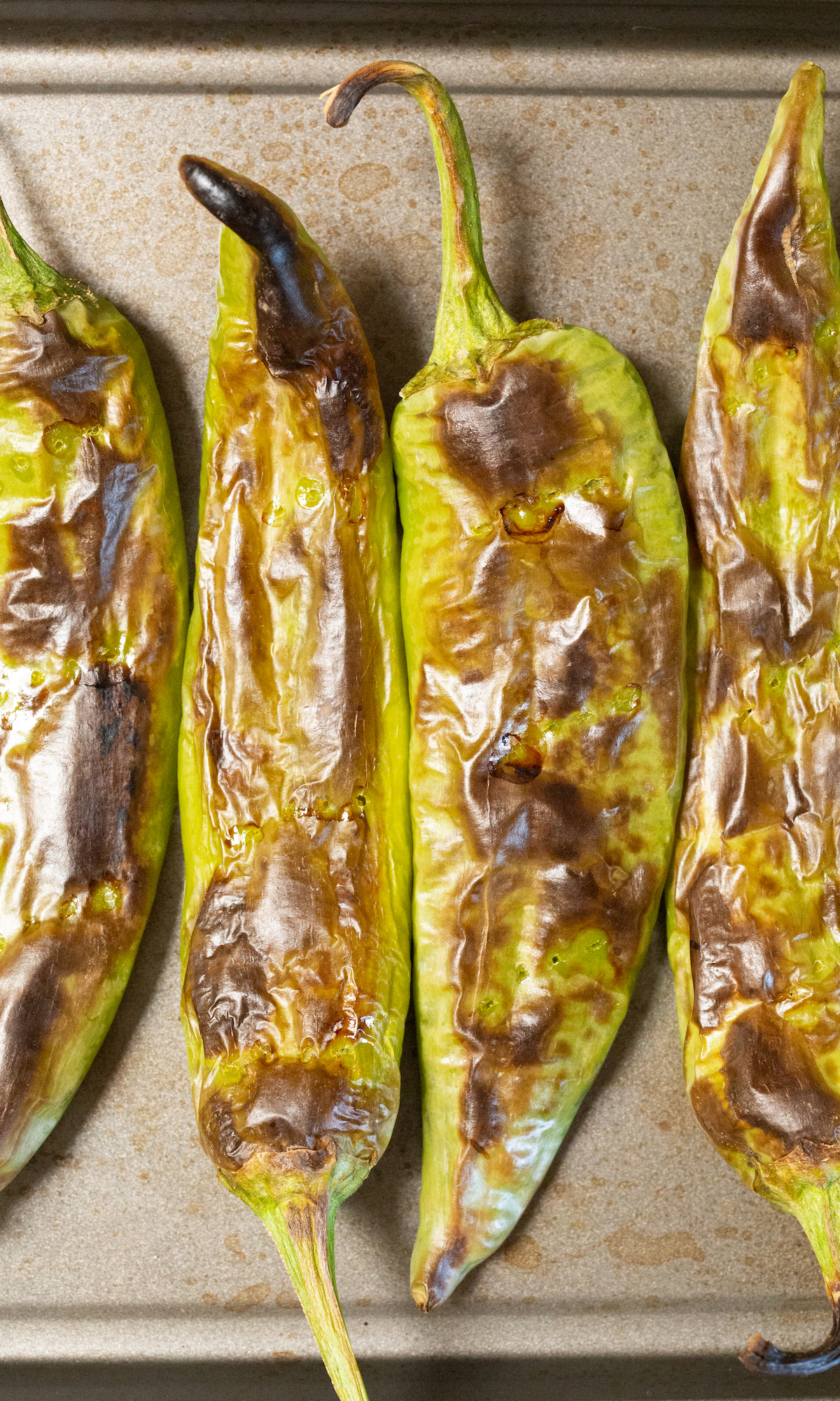 Close up of green roasted Hatch Chiles on a baking sheet.