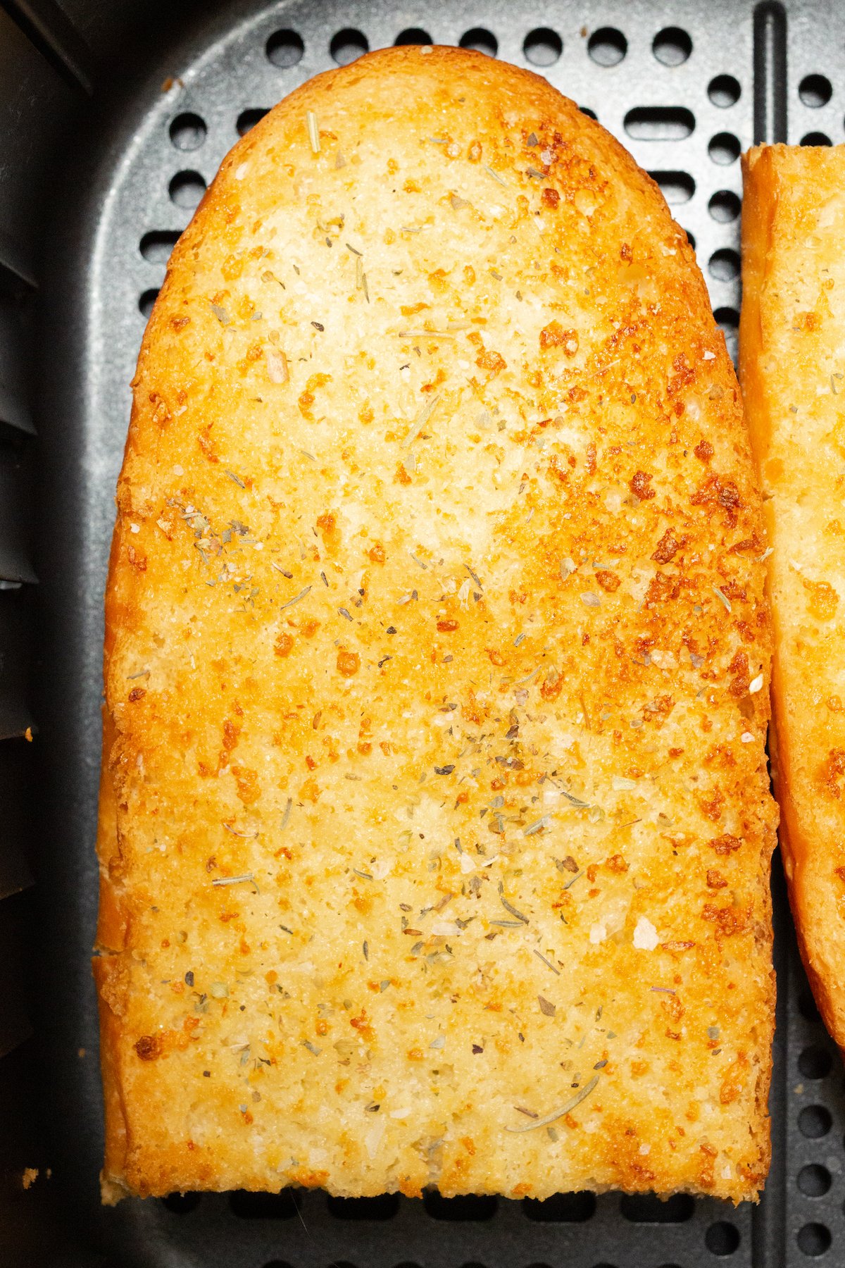 A piece of cooked garlic bread in the air fryer basket.