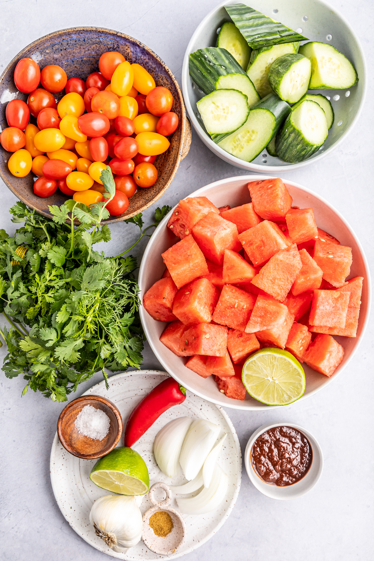 All the ingredients to make watermelon gazpacho in small prep bowls or plates.