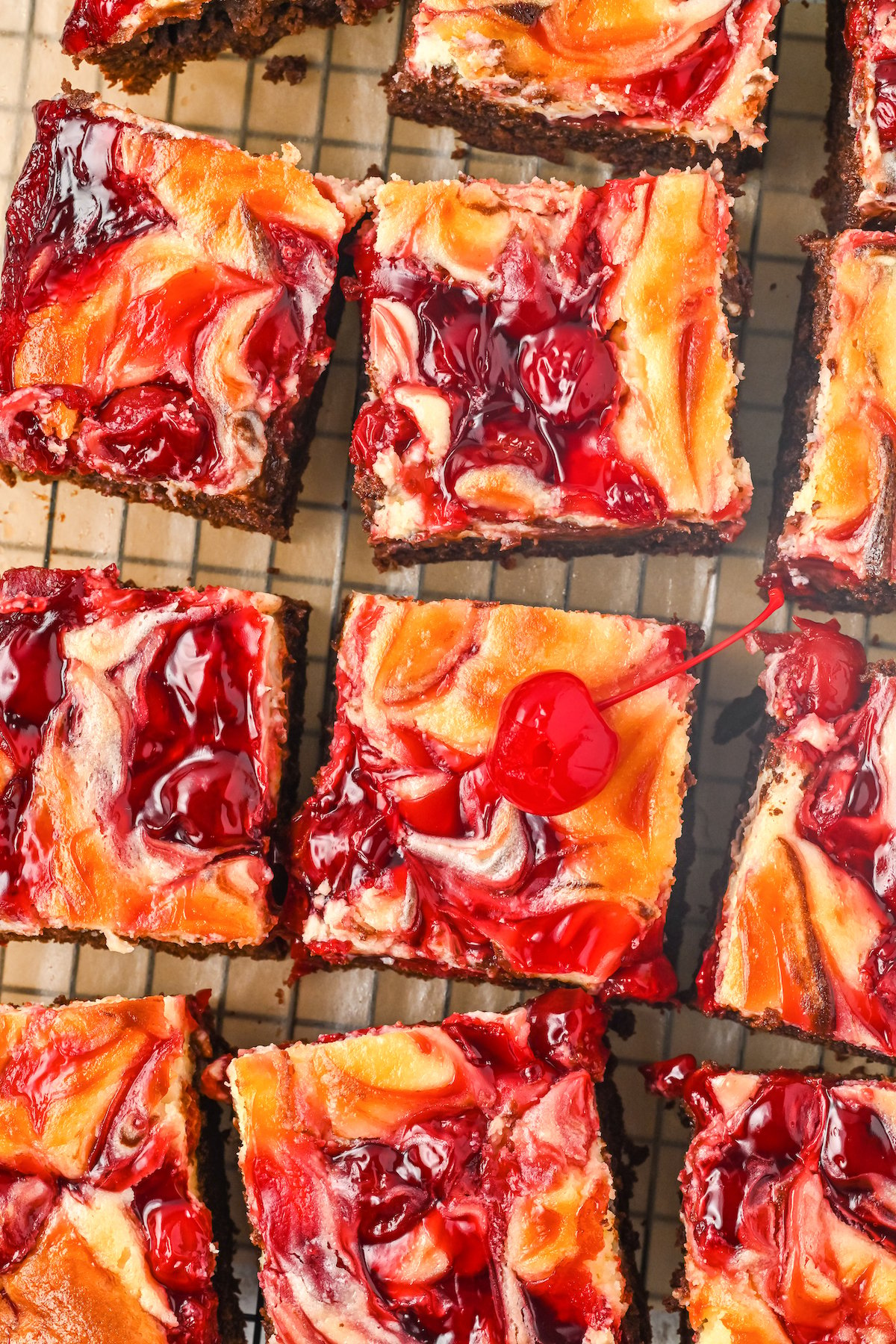 12 cut squares of cherry cheesecake brownies on a cooling rack.
