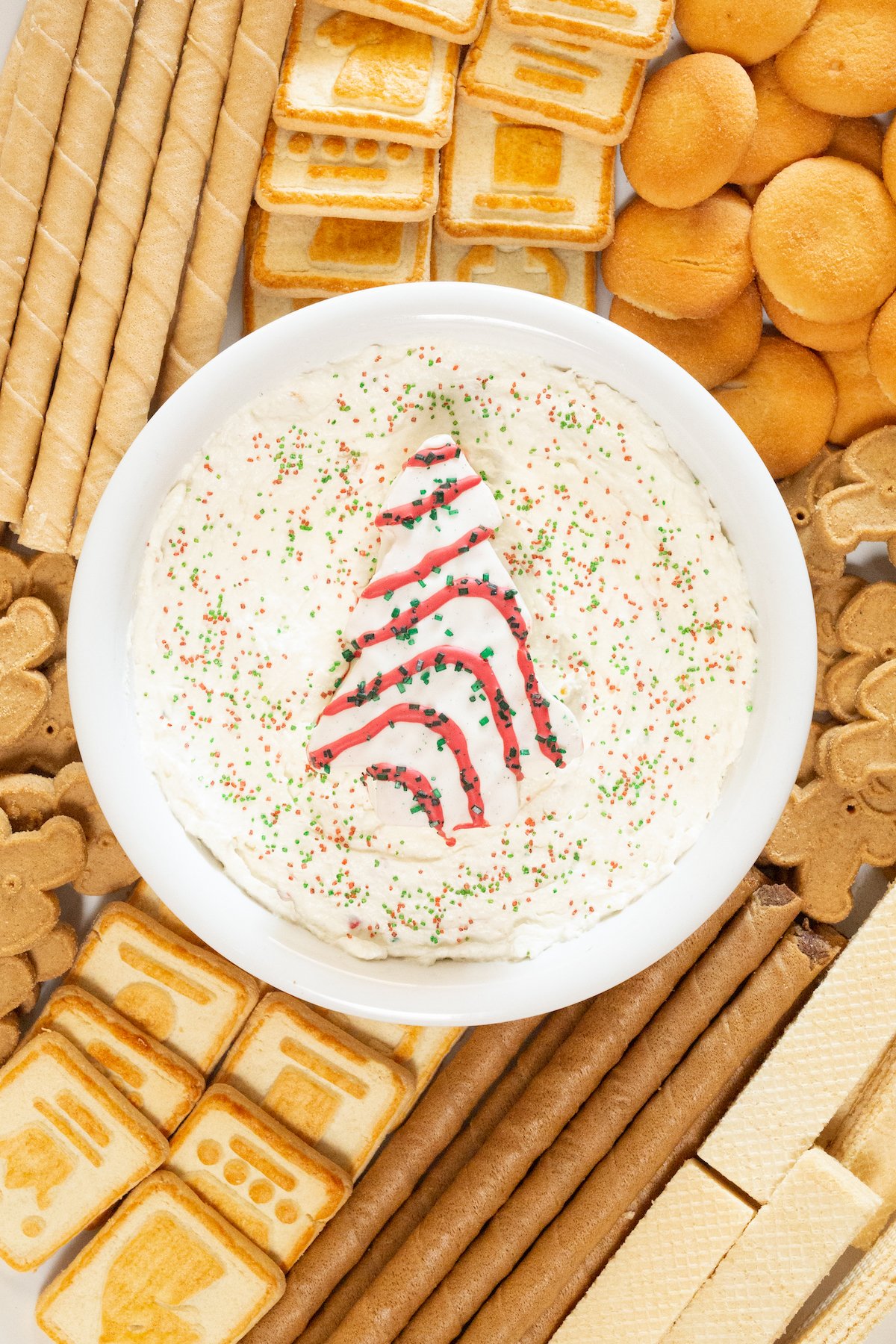 Overhead view of a platter with a bowl of Little Debbie's Christmas Tree Cake Dip in the center surrounded by a variety of cookies.