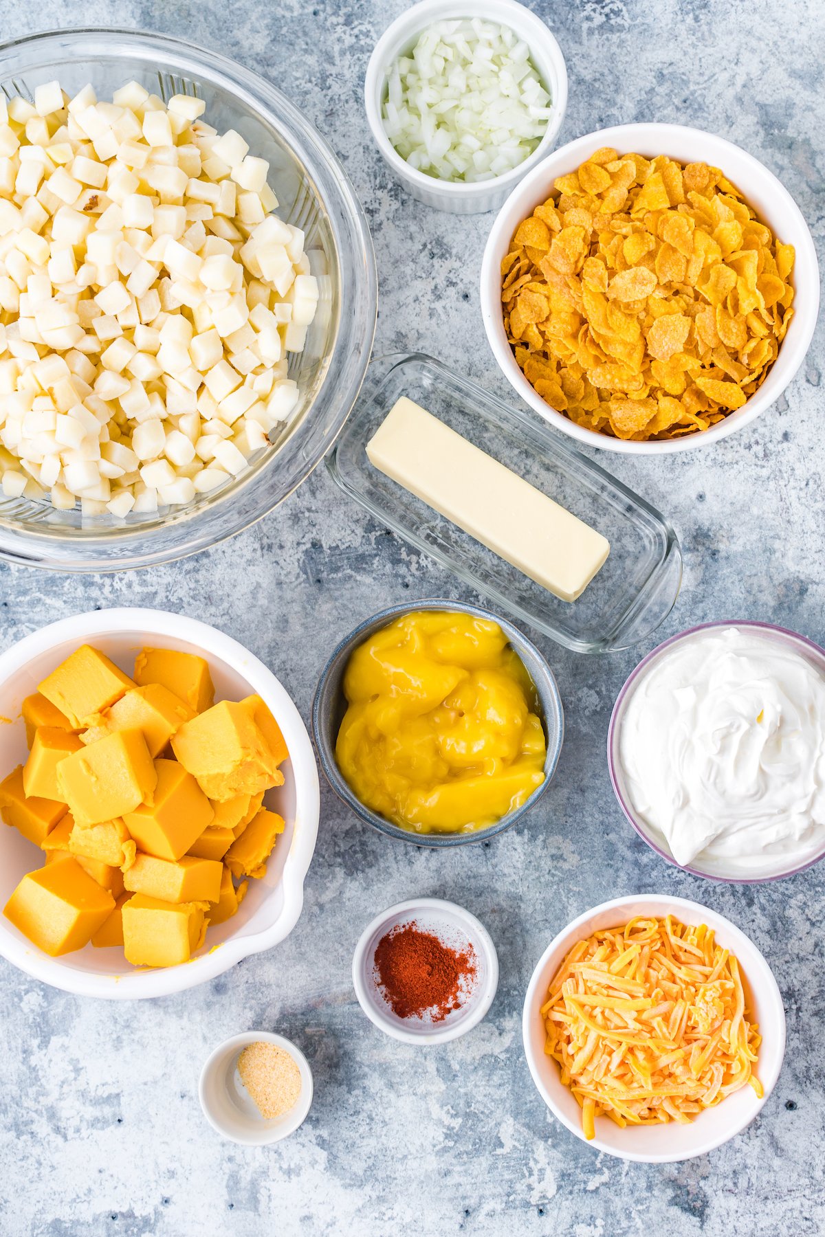 All the ingredients to make funeral potatoes in prep bowls on a countertop.