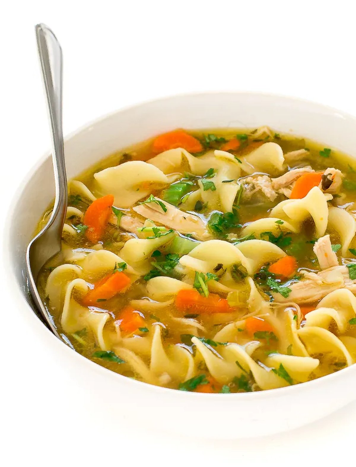 A bowl filled with Instant Pot chicken noodle soup on a white background.