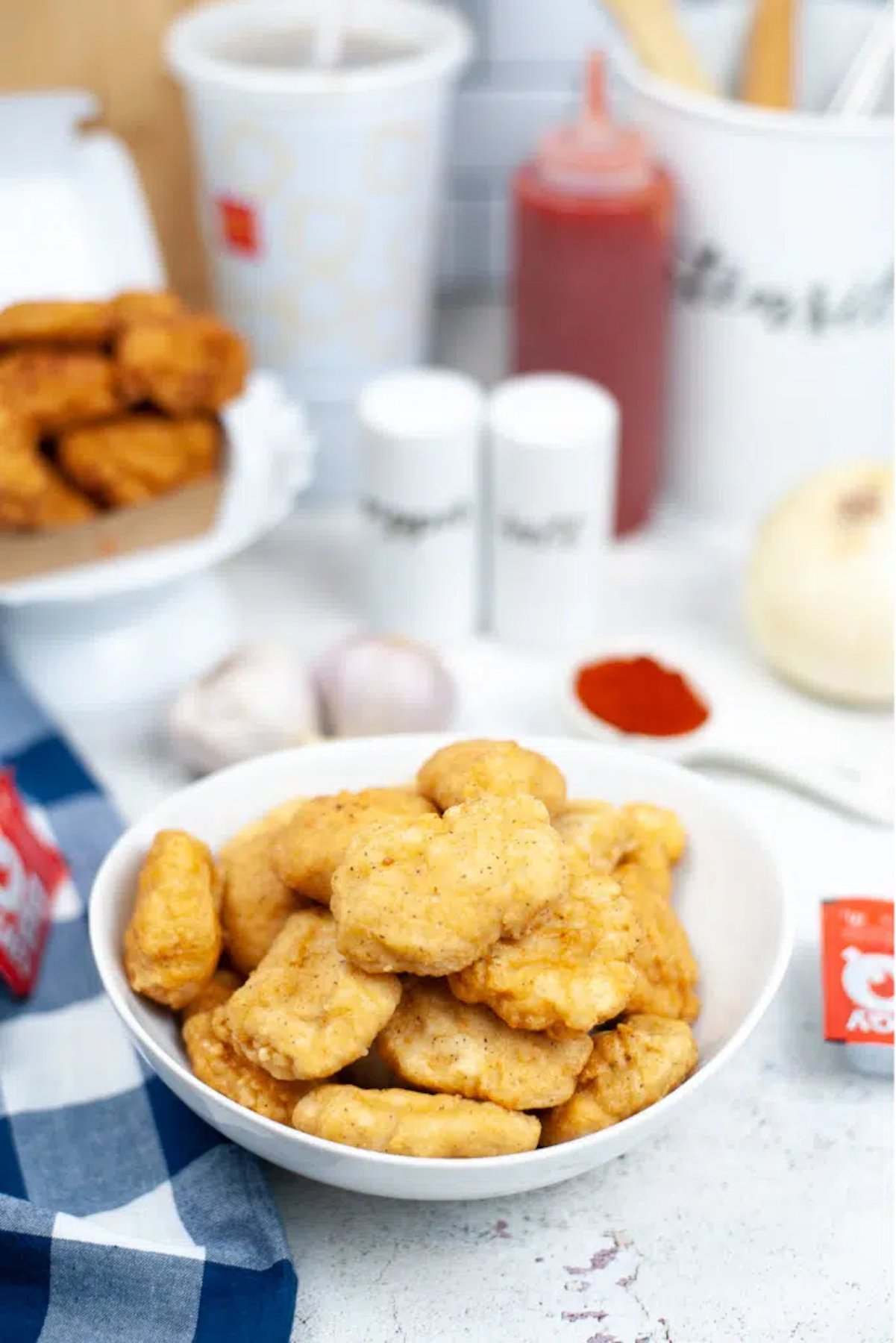 A bowl filled with homemade McDonald's chicken nuggets. BBQ sauce and a soft drink are out of focus in the background.