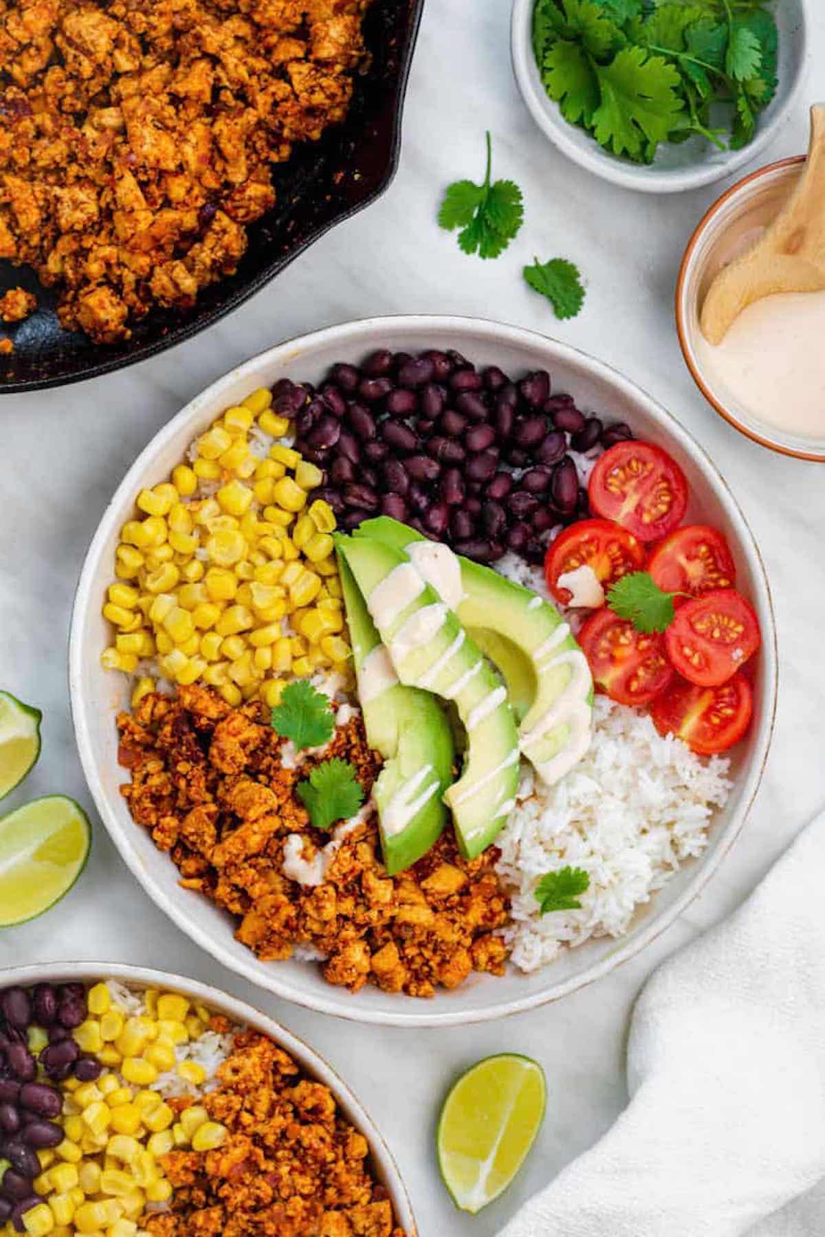 A bowl filled with rice, copycat chipotle sofritas, corn, black beans, cherry tomatoes, avocado, and cilantro.