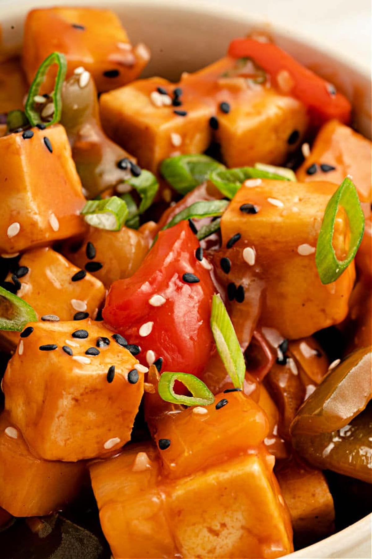 Chopped chicken and vegetables covered in copycat sweet & sour sauce and garnished with sliced green onion and sesame seeds.
