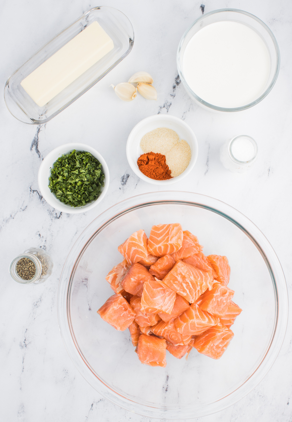 All the ingredients needed to make air fryer salmon bites in prep bowls on a marble counter top.