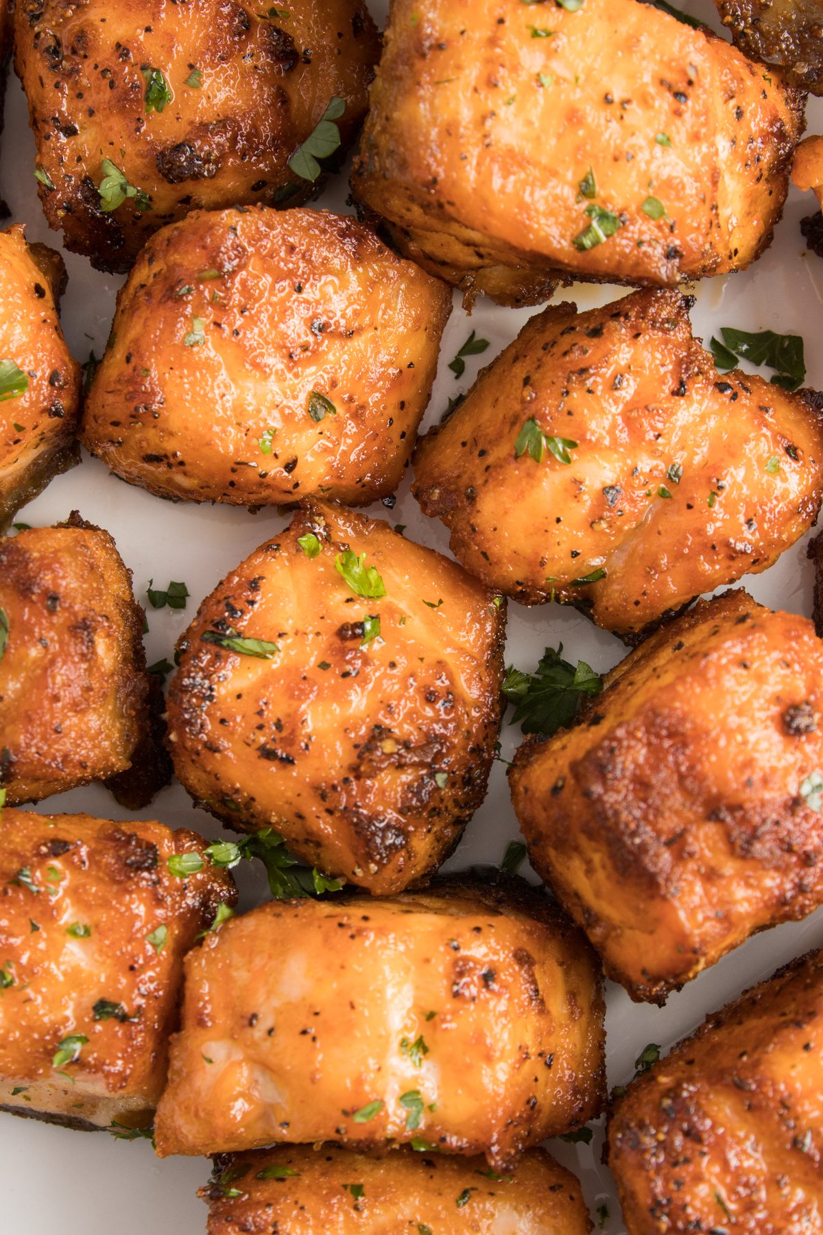 Close up of several air fryer salmon bites garnished with chopped parsley.