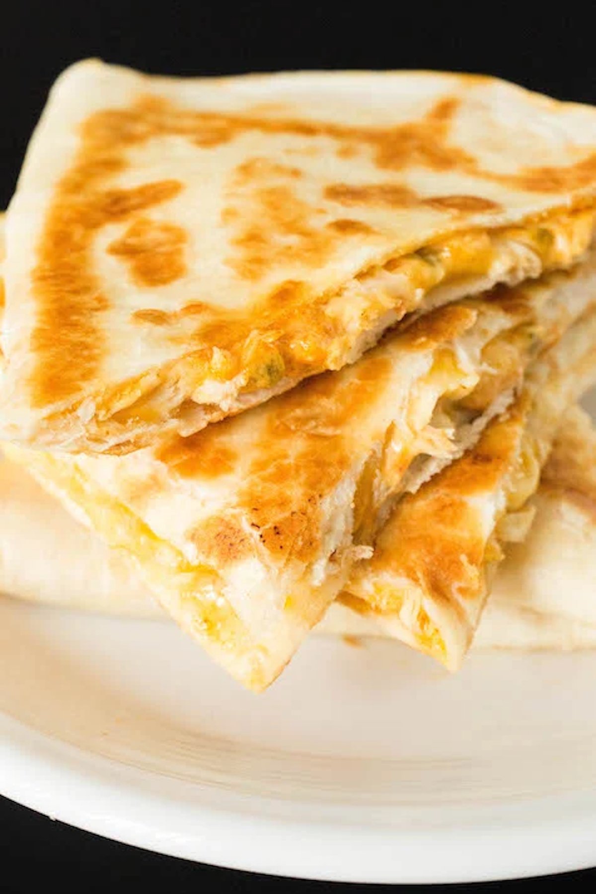 A slices of homemade Taco Bell quesadilla stacked on top of each other on a small white plate.