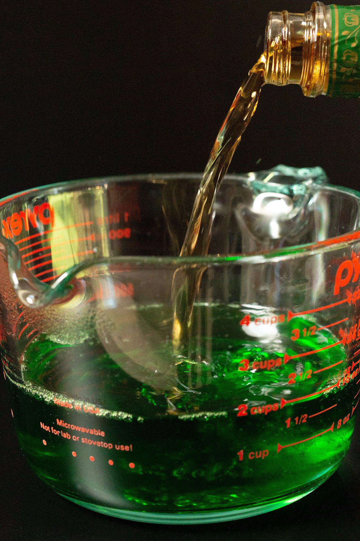 Crown Apple whisky poured from the bottle into a large measuring cup with green apple gelatin.