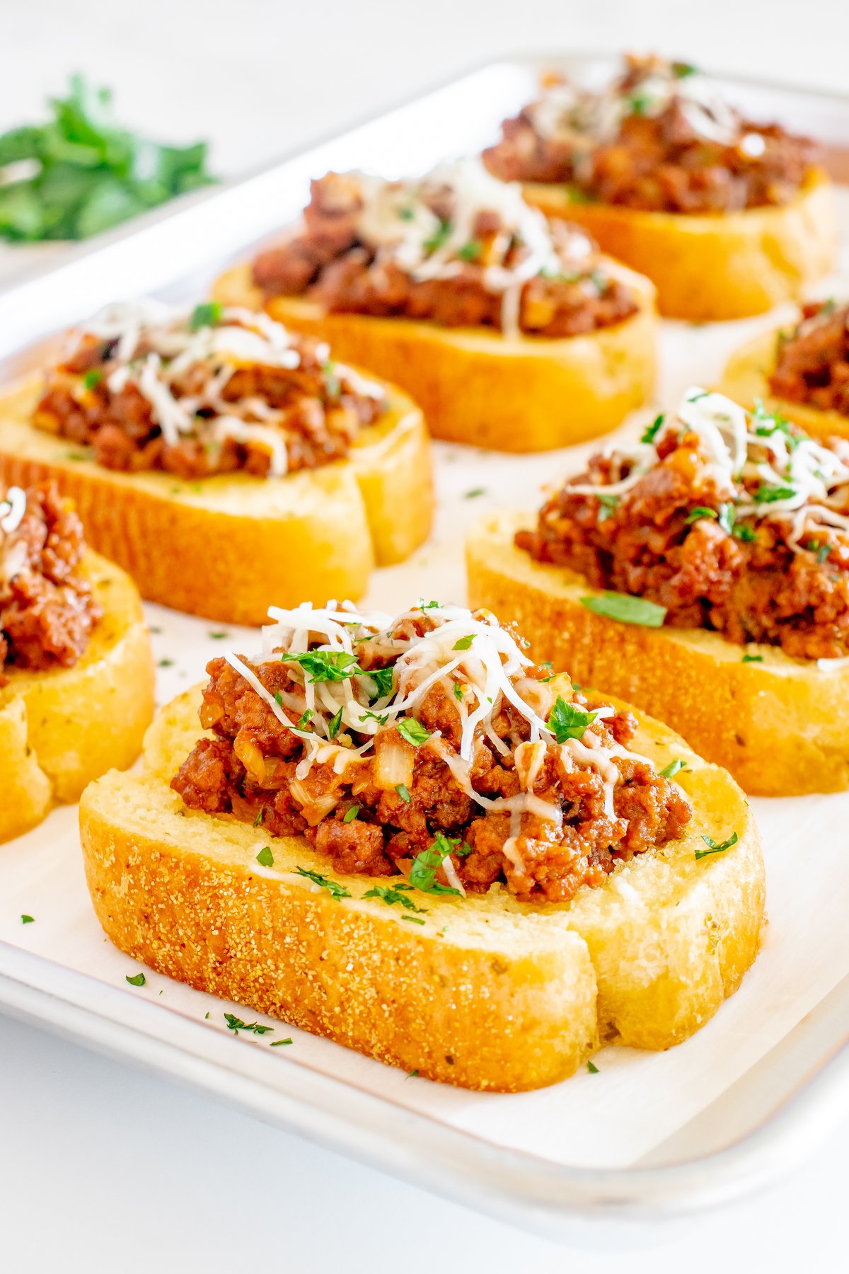 Sheet pan with 8 pieces of Texas Toast each piled high with sloppy joe filling and topped with shredded mozzarella cheese.