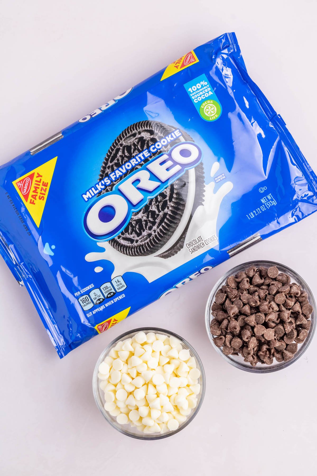 A package of Oreo cookies next to prep bowls of milk chocolate chips and white chocolate chips.