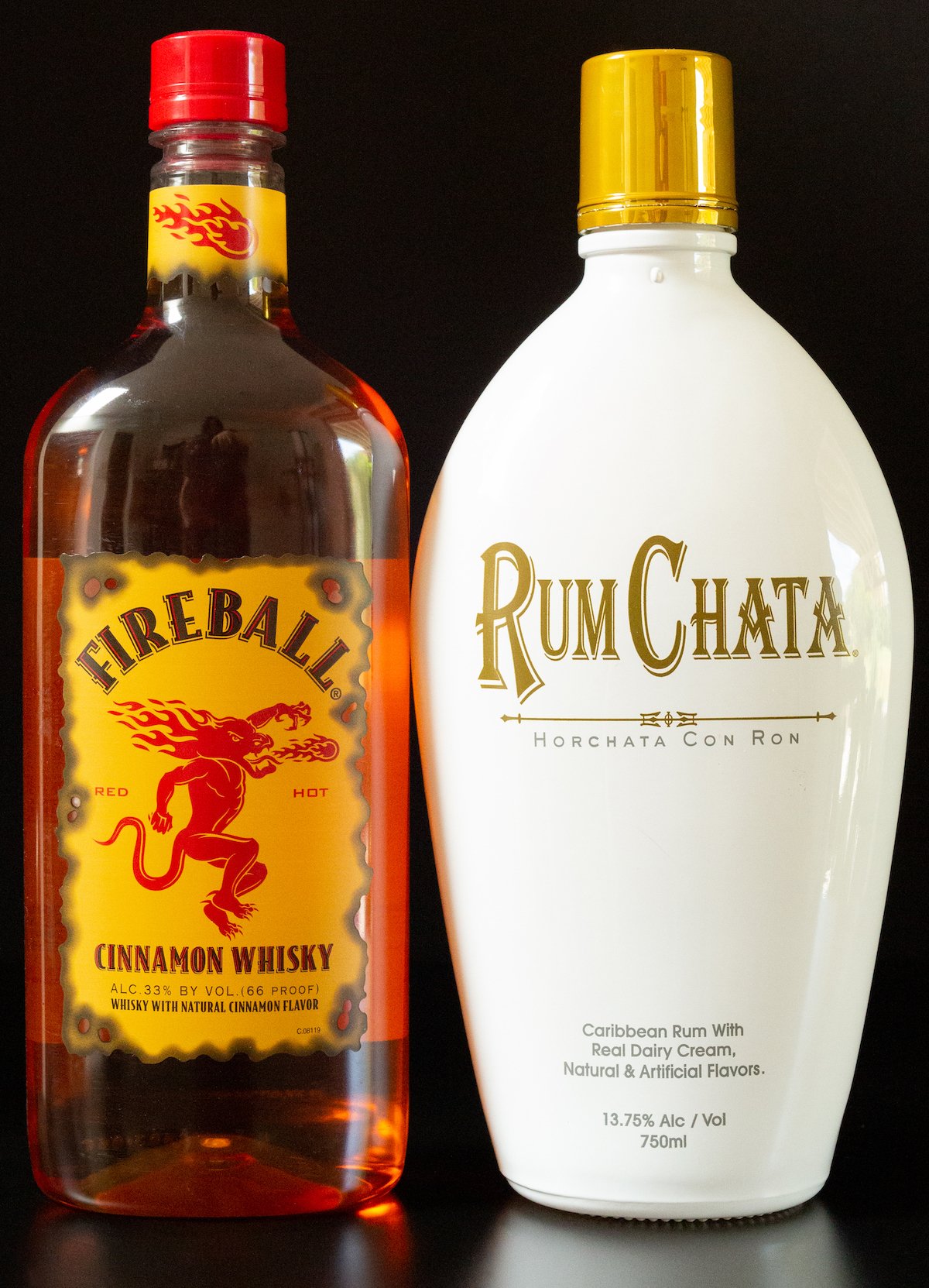 A bottle of Fireball whiskey and RumChata on a black background.