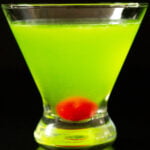 A stemless martini glass with a neon green Japanese Slipper cocktail on a black background.