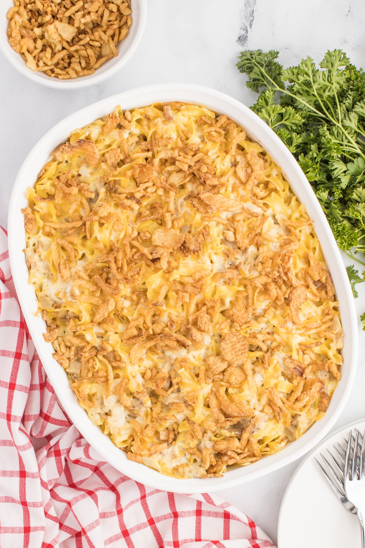 Overhead view of a white baking dish filled with a cooked French onion chicken casserole. A red striped dish towel is in the background.