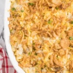 Close up of French onion chicken casserole topped with crispy onions in a white casserole dish.