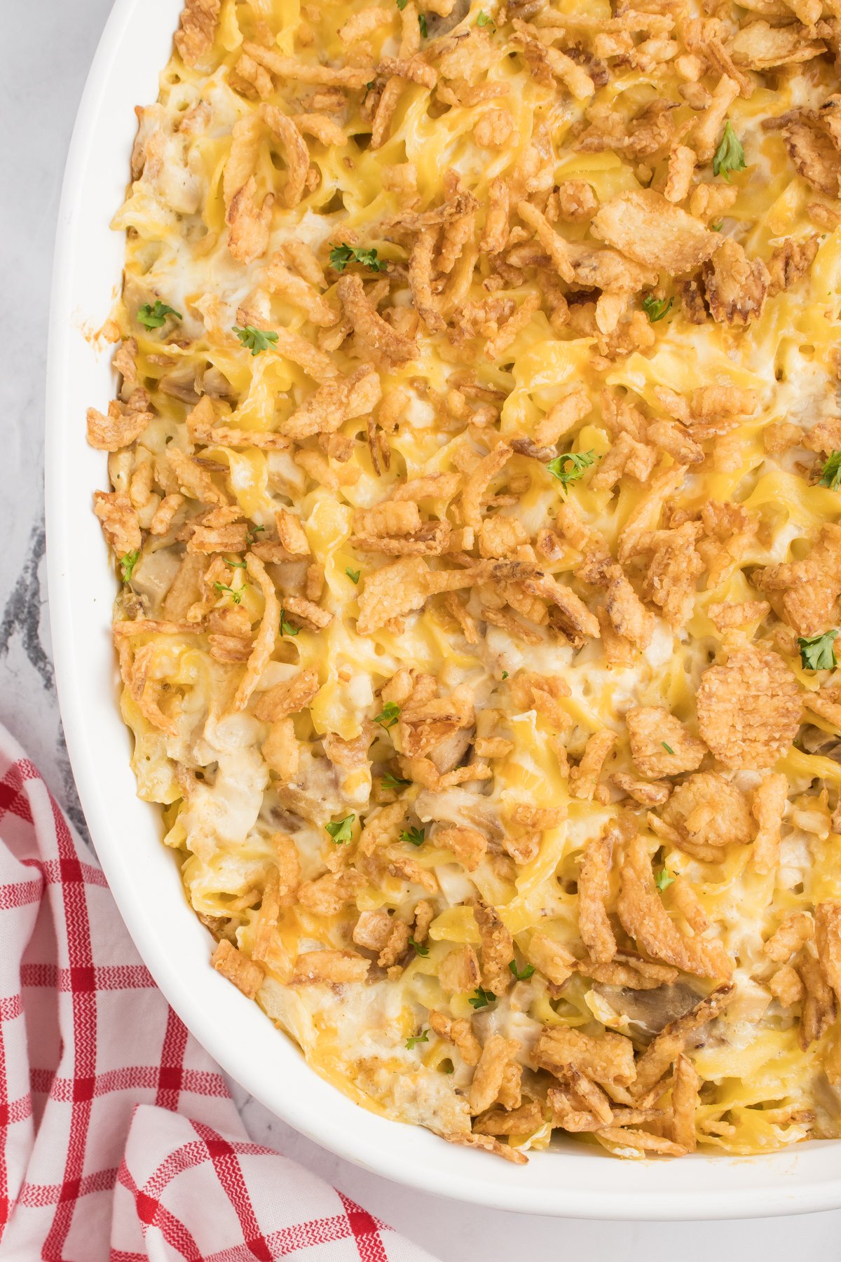 Close up of French onion chicken casserole topped with crispy onions in a white casserole dish.