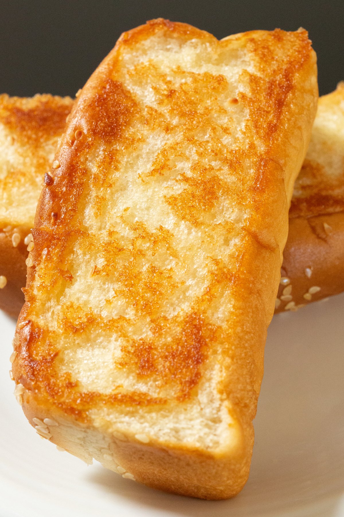 A slice of browned copycat Raising Canes bread lays on top of another on a small white serving plate.