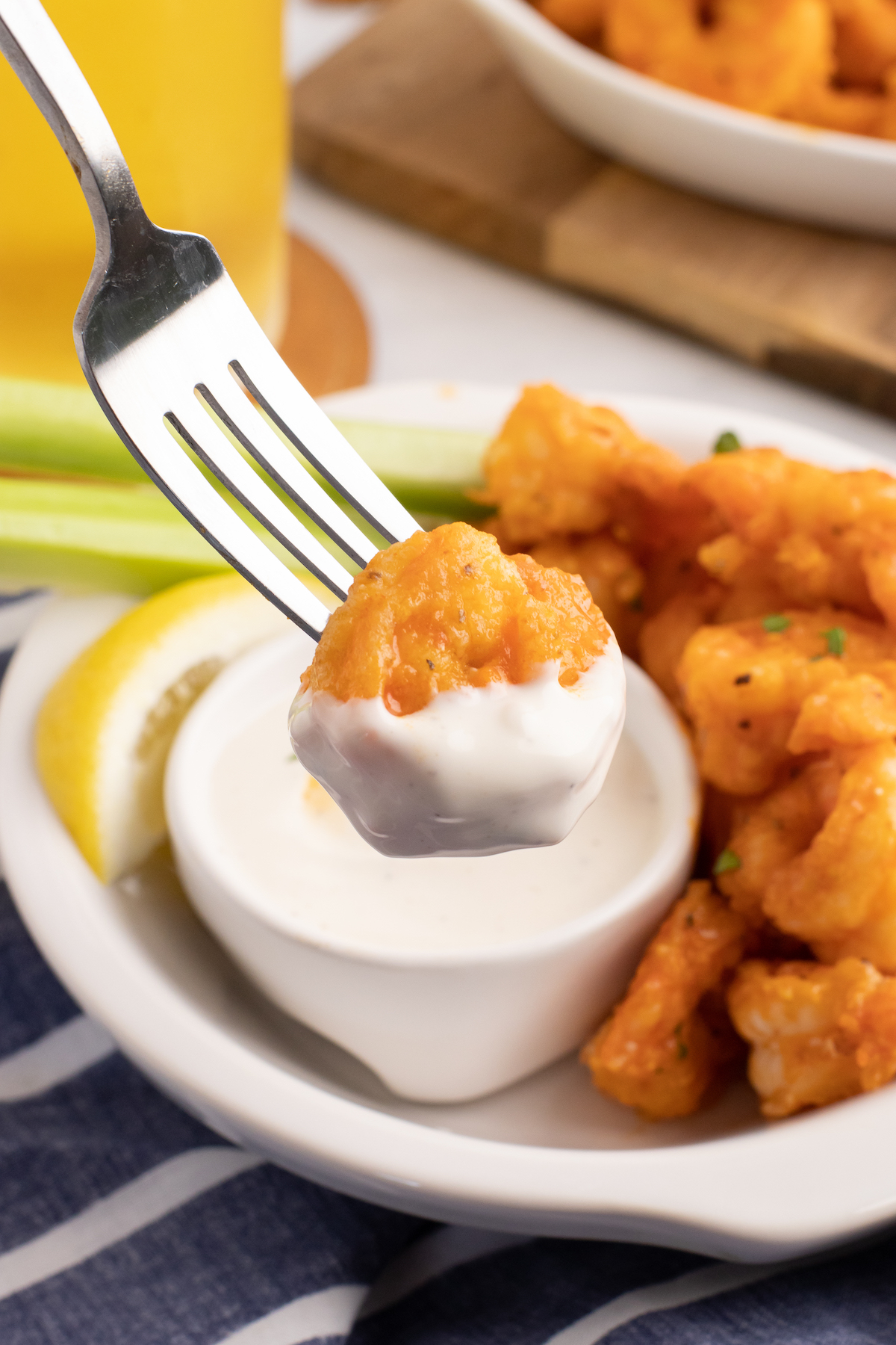 A fork holds up a buffalo shrimp that has been dipped in ranch dressing.