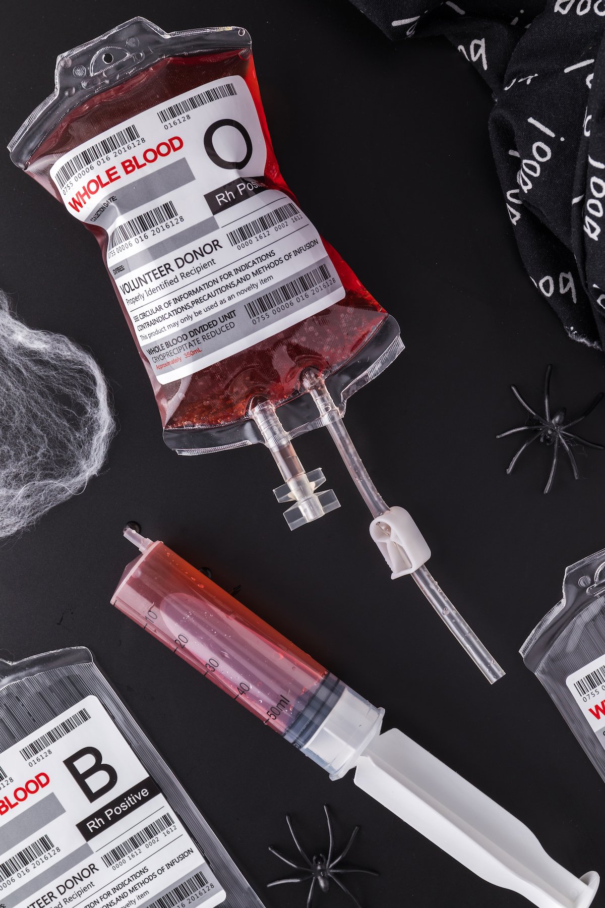 A fake "IV bag" has been filled with Halloween punch that looks like blood. A plastic syringe sits next to it.