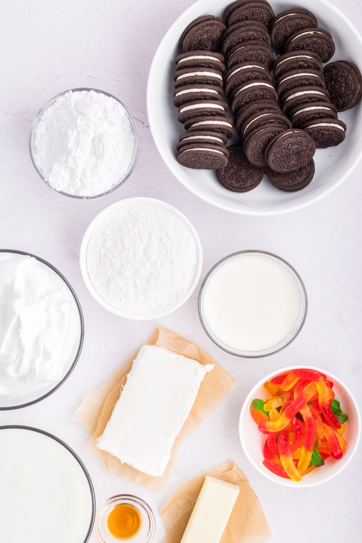 All the ingredients needed to make Oreo dirt cake arranged in glass prep bowls.