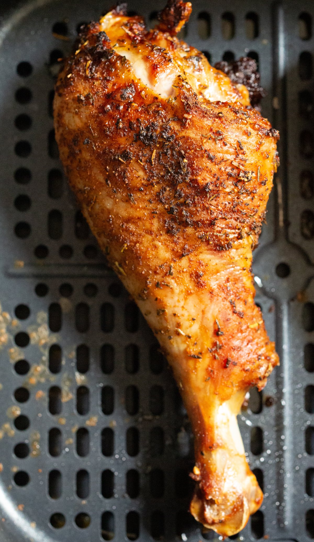 A single cooked turkey leg in an air fryer basket.