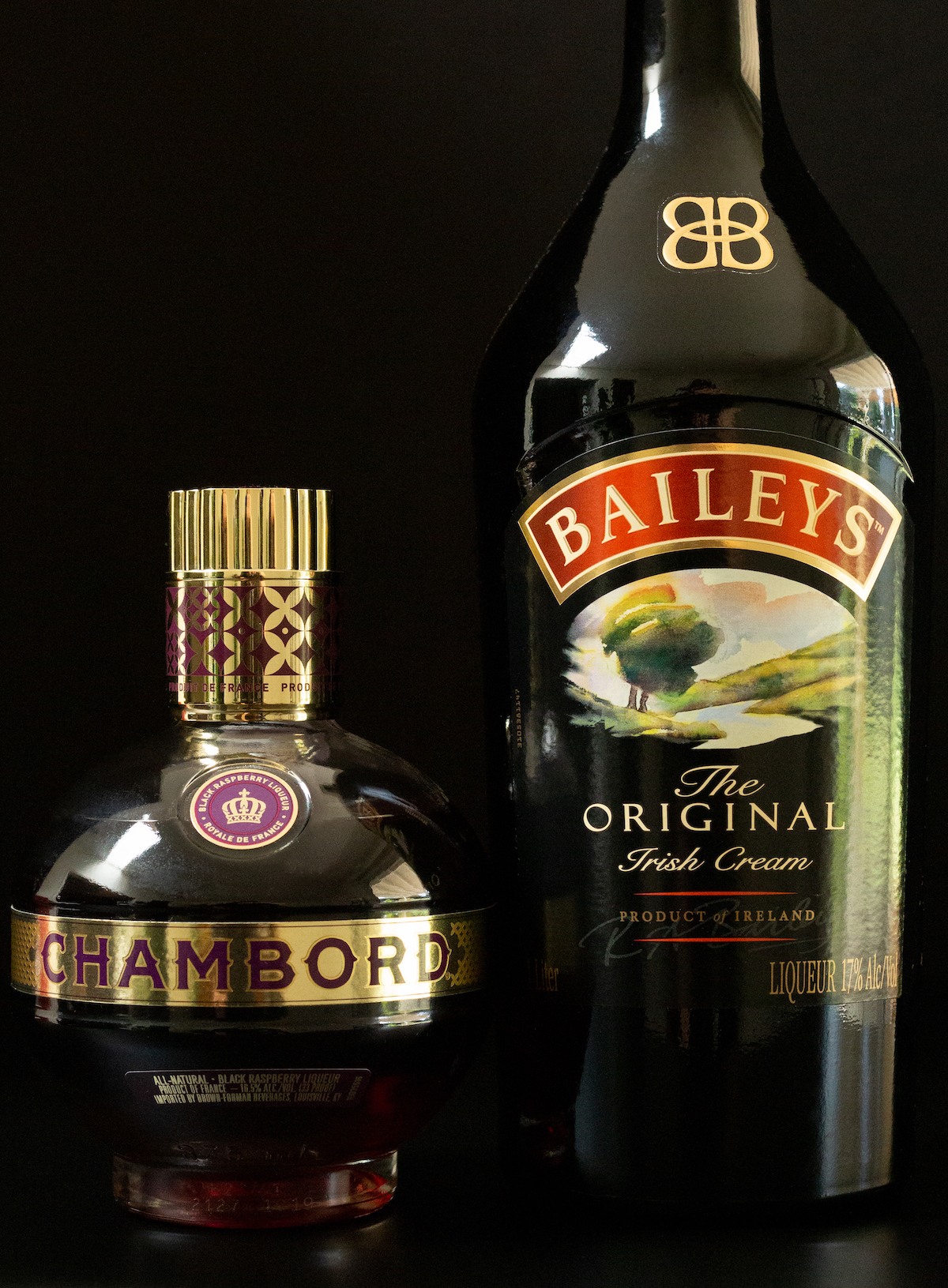 A bottle of Chambord and a bottle of Bailey's Irish Cream on a black background.