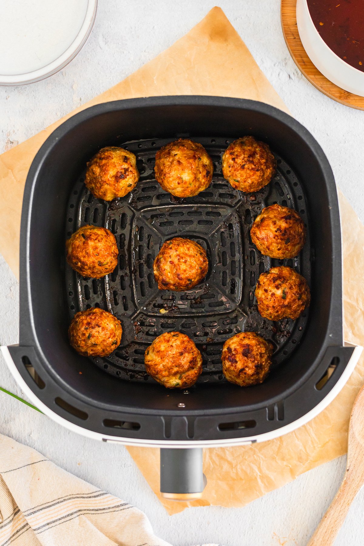 An air fryer basket with 10 cooked firecracker meatballs.