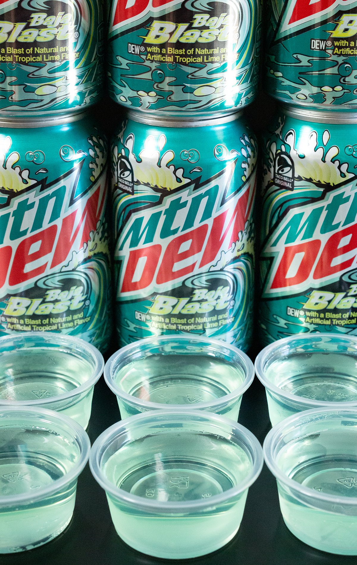 Three rows with two baja blast jello shots in each row. Stacked cans of the soda in the background.