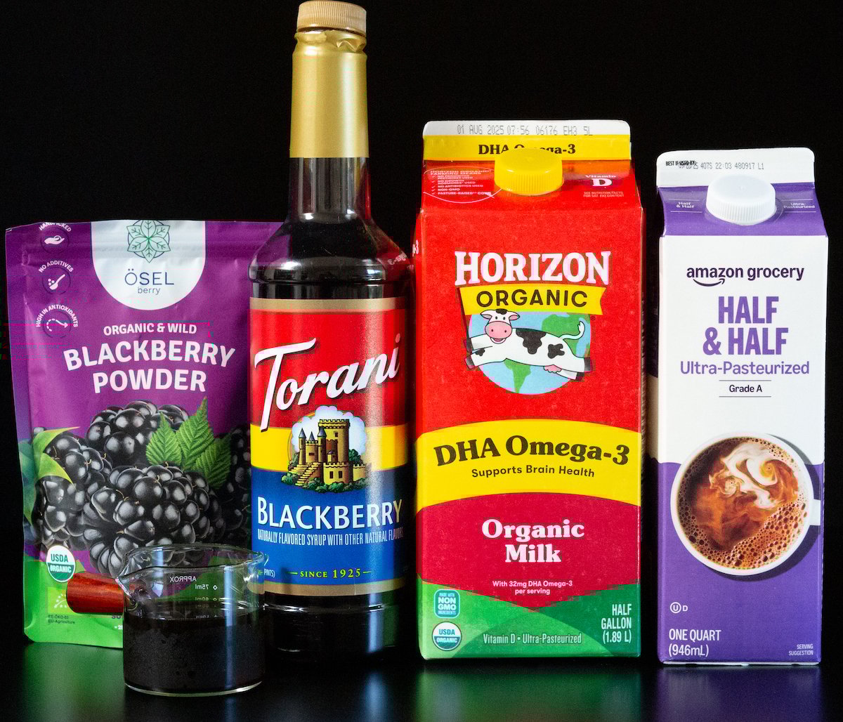 Blackberry powder, blackberry syrup, organic milk, half and half, and a double shot of espresso on a black background.