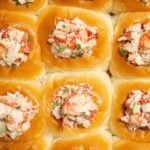 Overhead view of a pack of 12 Hawaiian rolls that have had holes cut in the middle and stuffed with cold lobster salad.