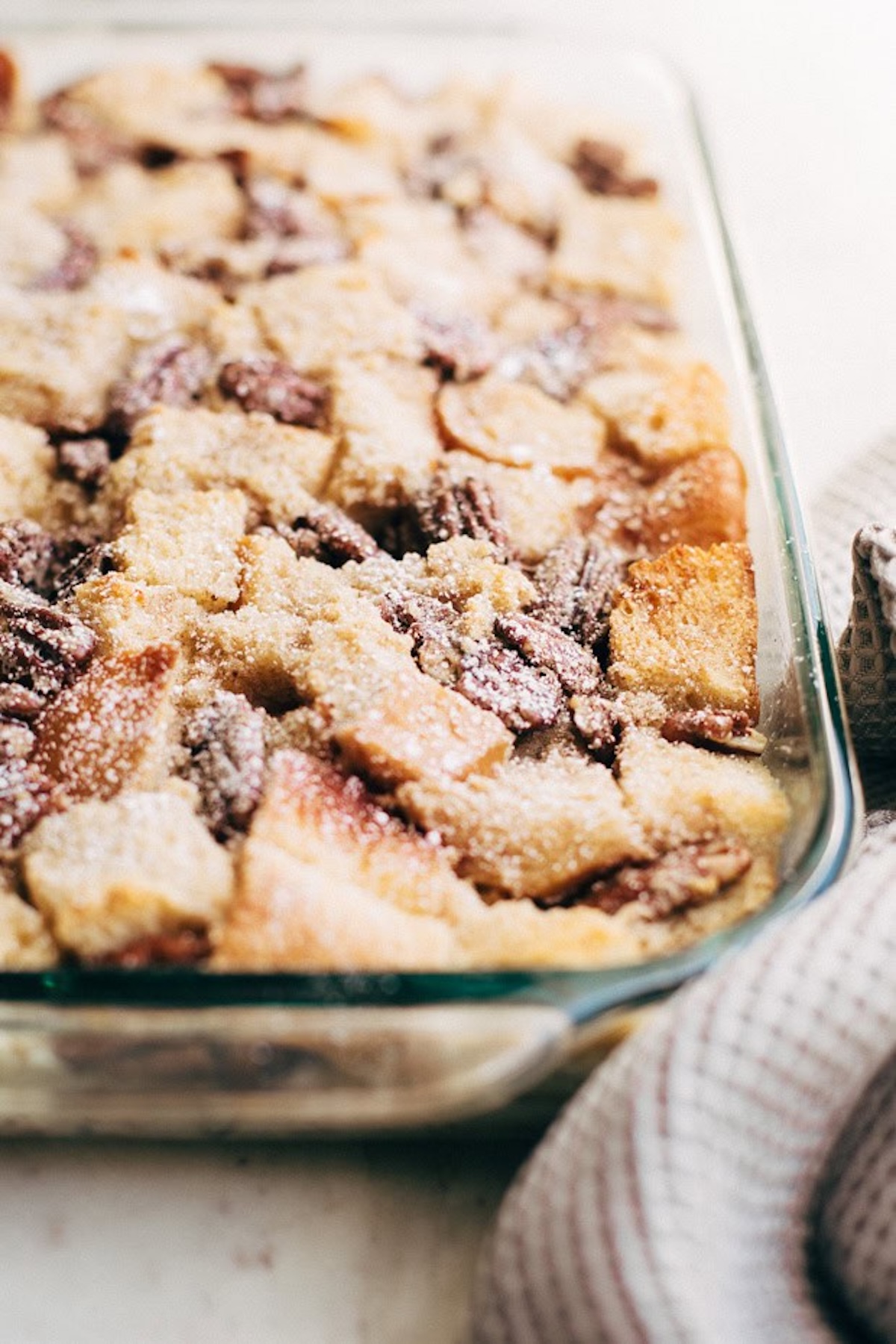 A 16x9 class baking dish filled with a bread pudding that has candied pecans.