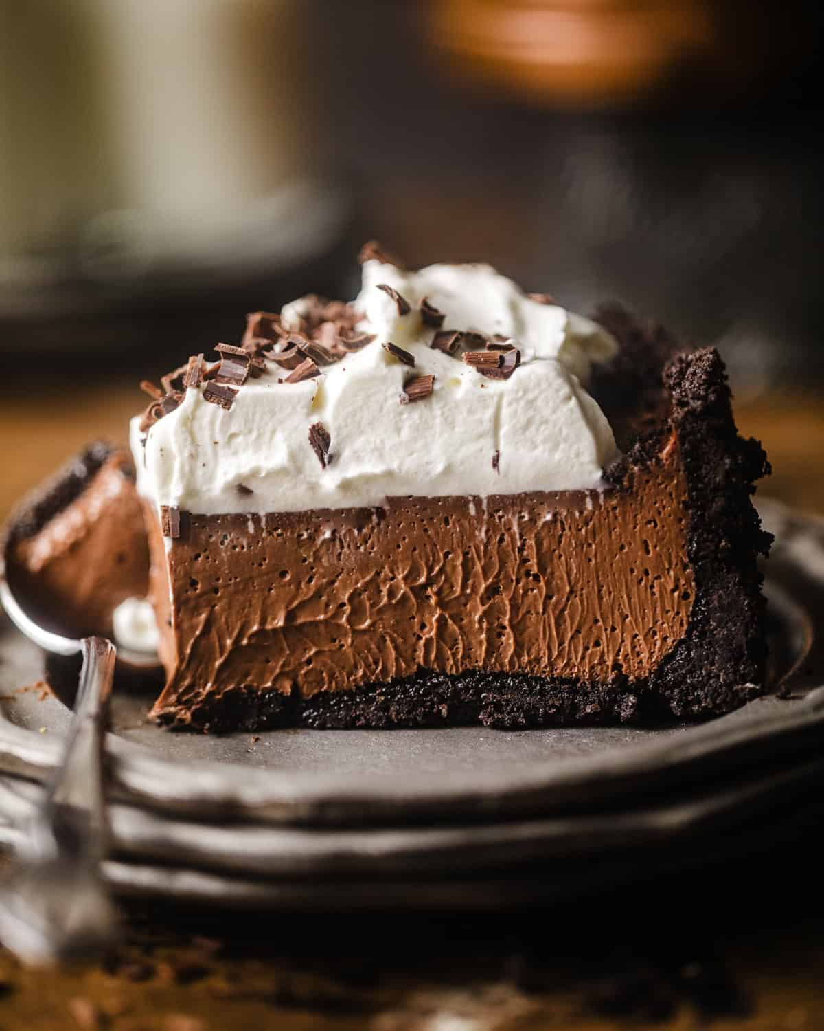 A thick chocolate pie that has a generous layer of whipped cream garnished with chocolate shavings.
