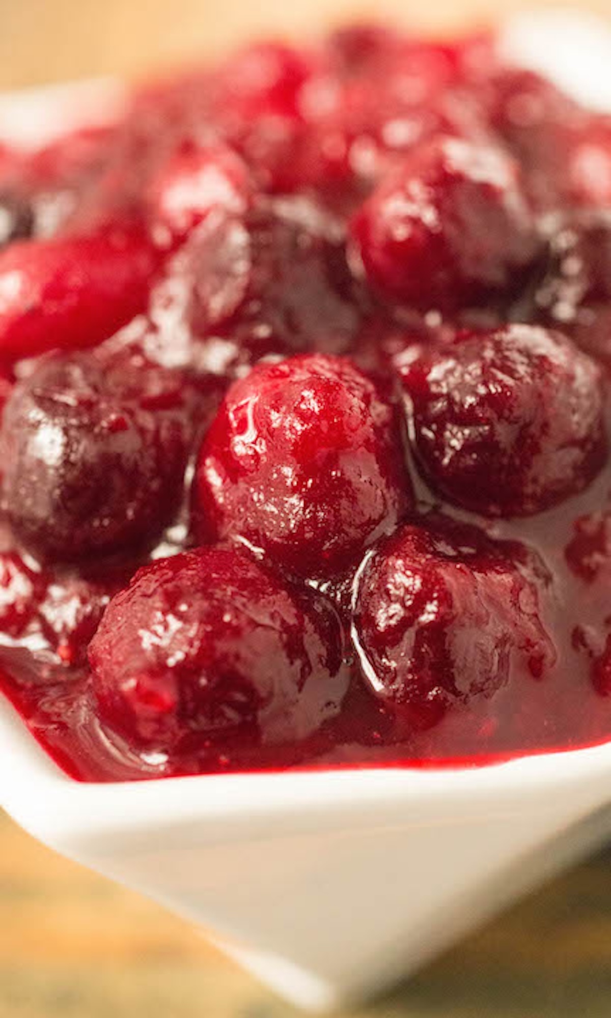 A small white serving dish filled with a cranberry compote that features whole bright red cranberries.