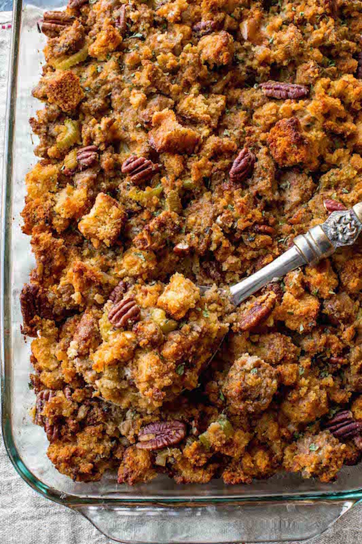 Overhead view of glass baking dish that's filled with a homemade stuffing that has whole pecans.