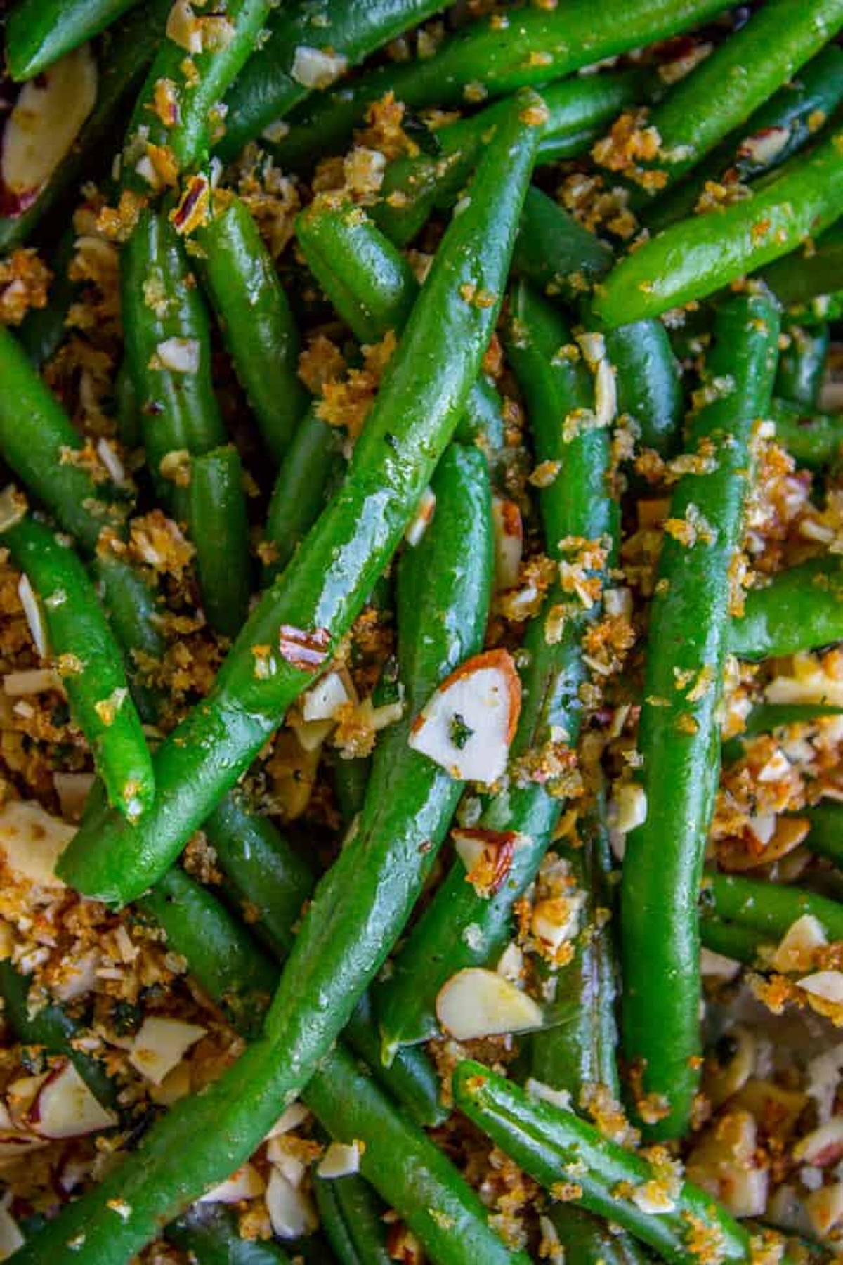 Fresh green beans have been cooked and topped with bread crumbs and chopped almonds.