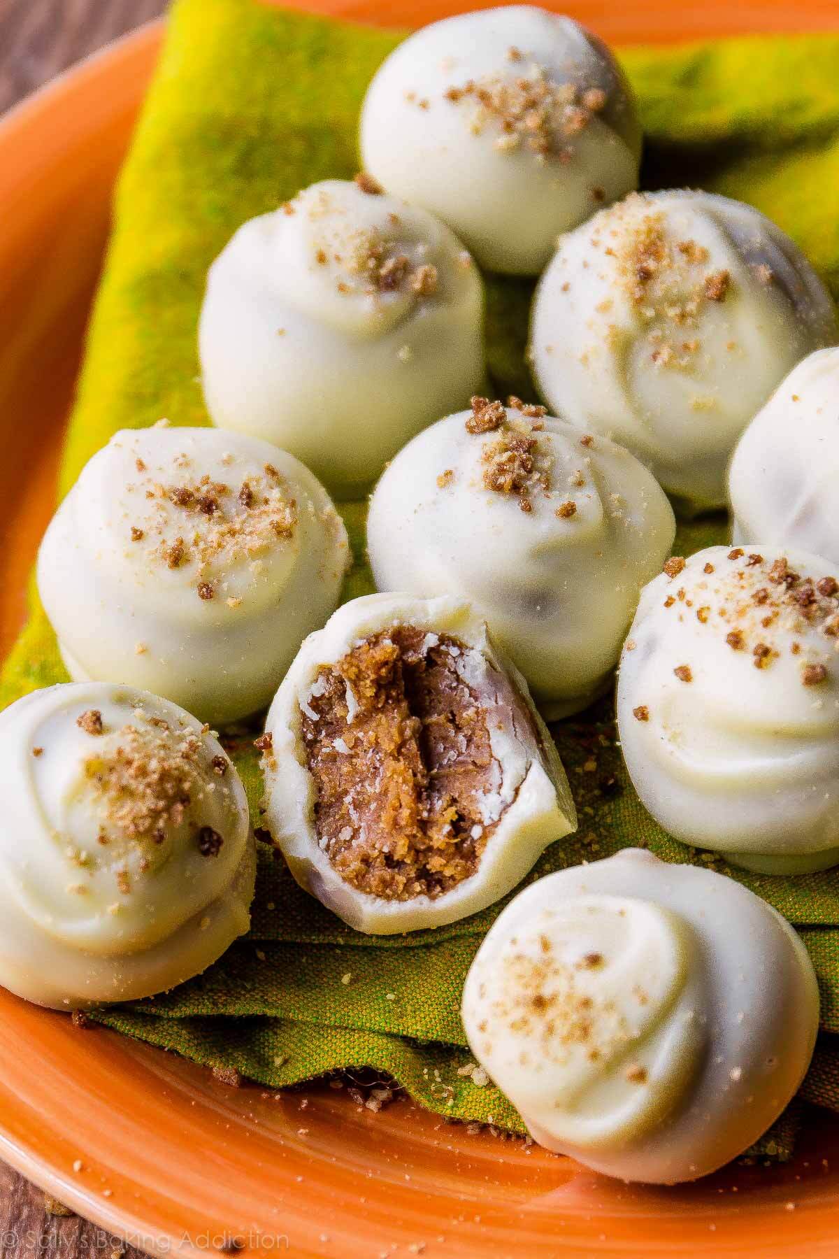 Ten palm sized dessert truffles coated in white chocolate and garnished with graham cracker crumbs.