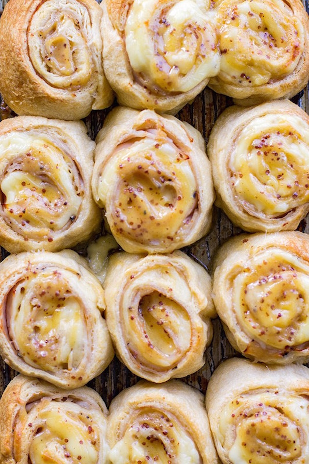 Nine baked puff pastry rolls that are filled with turkey slices and melted gouda cheese.